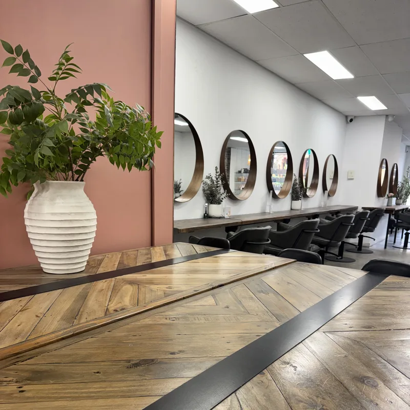 Terracotta feature wall, communal table and styling stations at Hair Management Co in Gymea